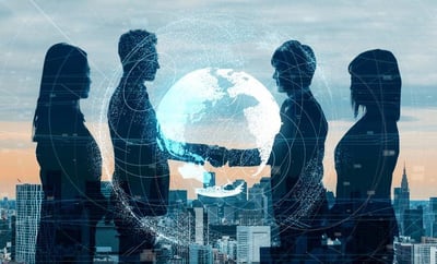Siluetas de cuatro directivos cara a cara alrededor de un globo terráqueo digital con un apretón de manos superpuesto, sobre un fondo de rascacielos al atardecer y una red de líneas de datos conectando el mundo.